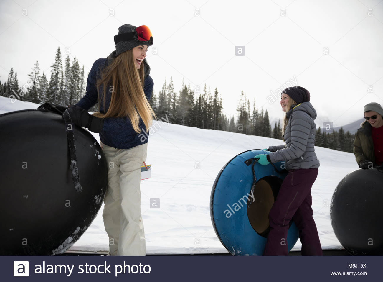 Friends carrying inner tubes in snow Stock Photo Alamy