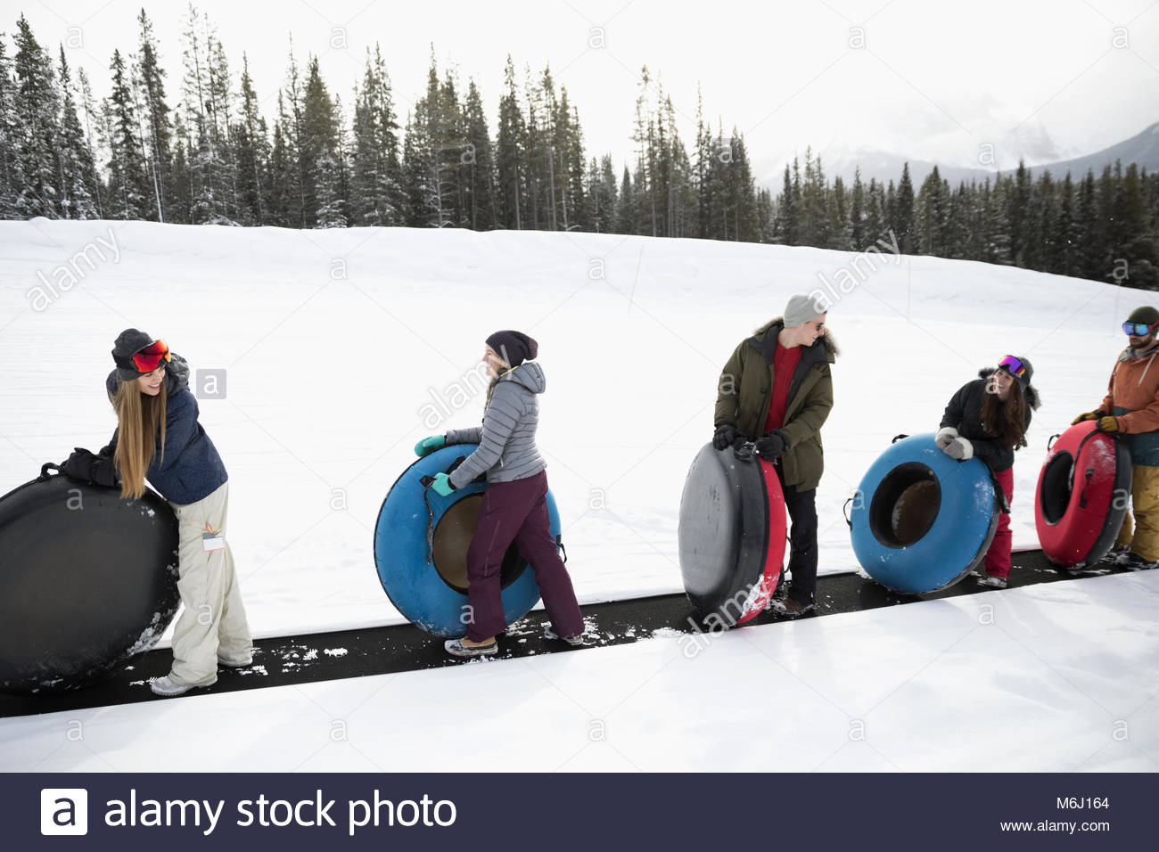Friends carrying inner tubes in snow Stock Photo Alamy