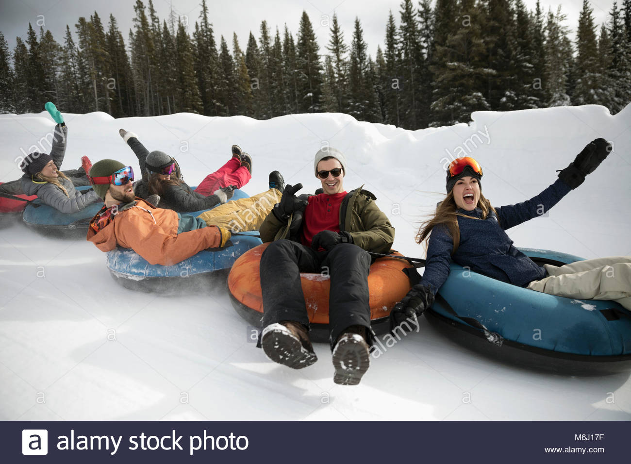 Portrait playful friends riding inner tubes in snow Stock Photo Alamy