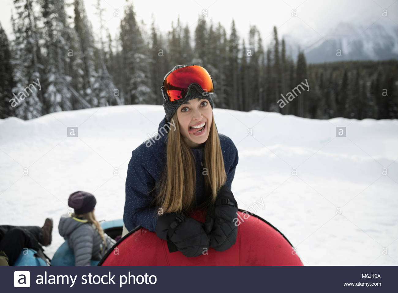 Portrait silly woman with inner tube making a face in snow Stock Photo