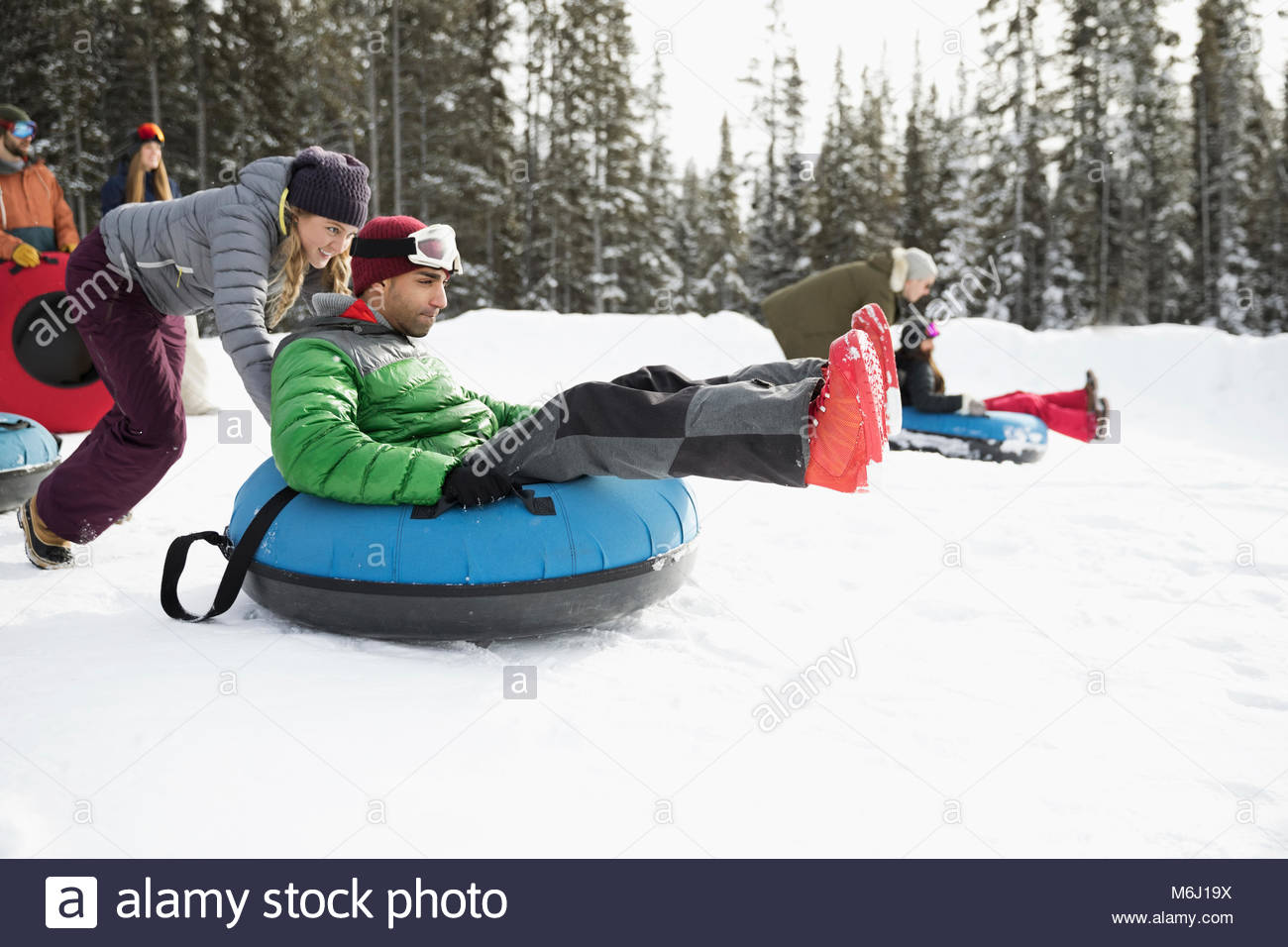 Friends racing, inner tubing in snow Stock Photo Alamy
