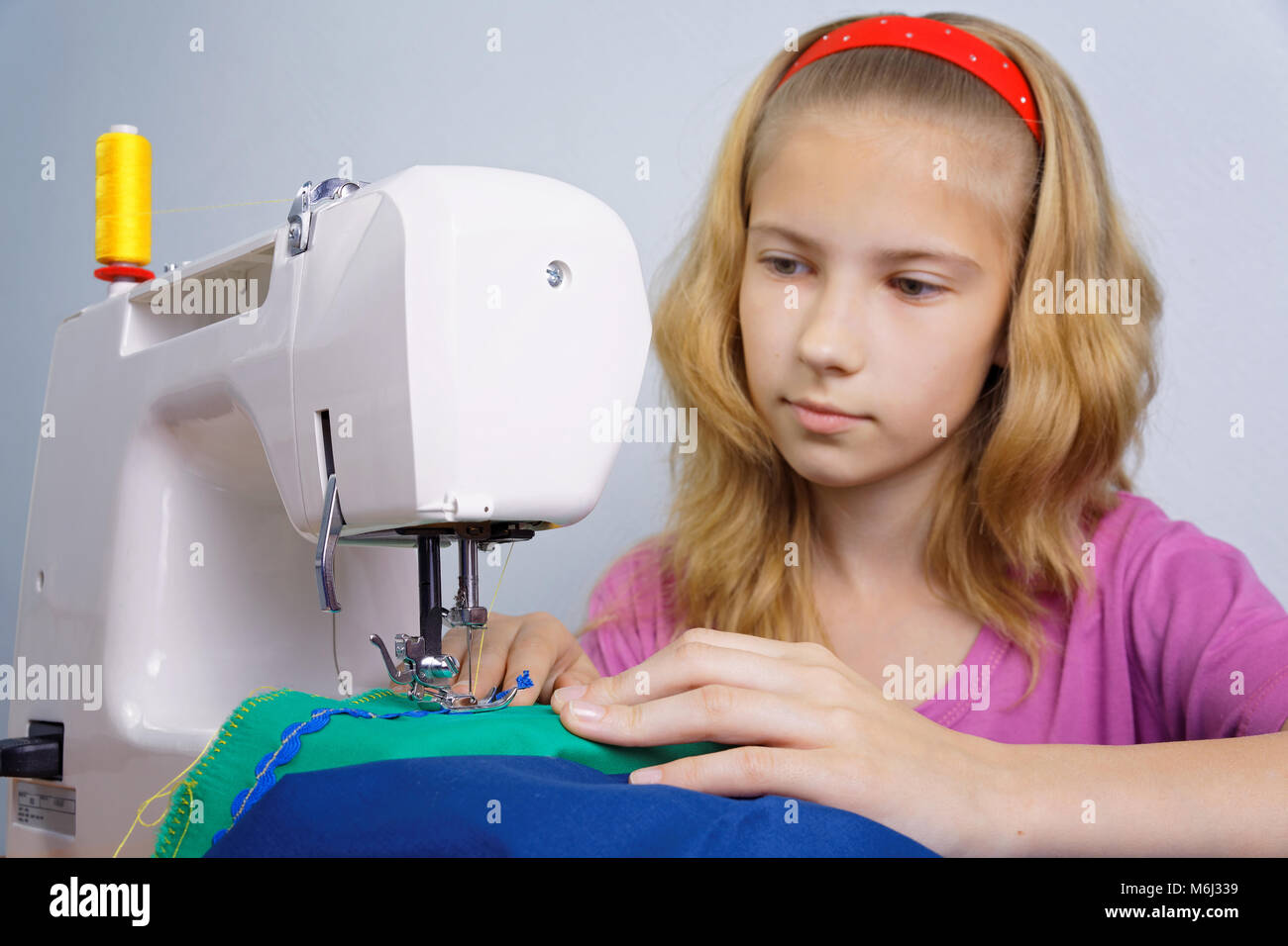 Girl teenager happy to sew on the sewing machine. Focus on her hands