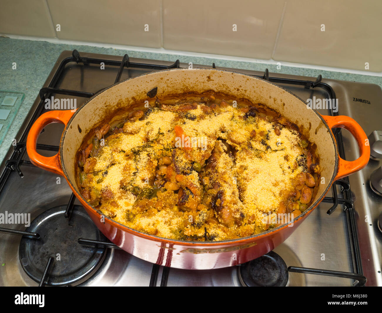 Casserole with a freshly cooked Cassoulet made from sausages bacon lardons and vegetables sprinkled with bread crumbs Stock Photo