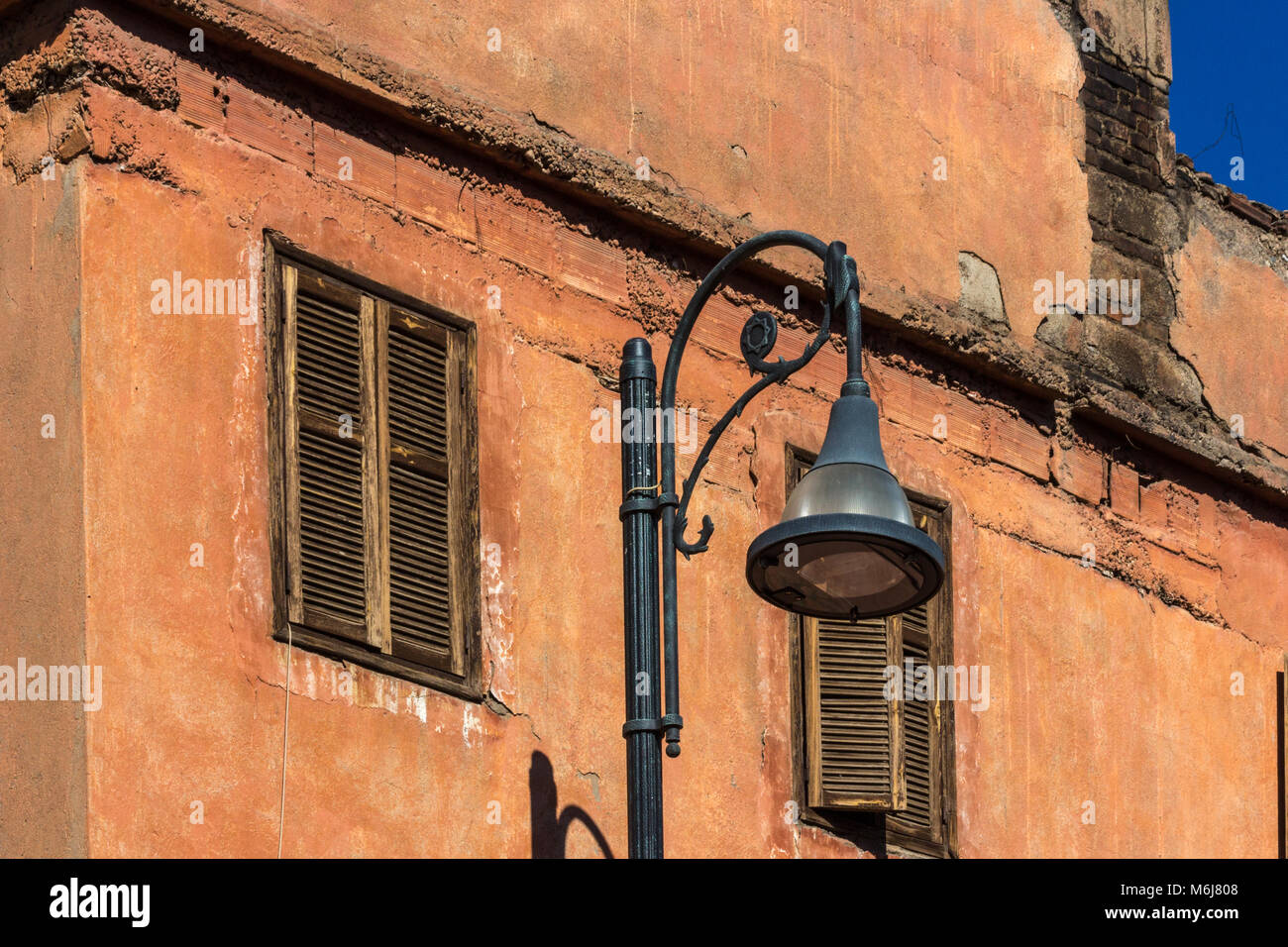 Street lamp against a terracotta-coloured building with old wooden shutters, against a dark blue sky. Marrakesh. Morocco. Stock Photo
