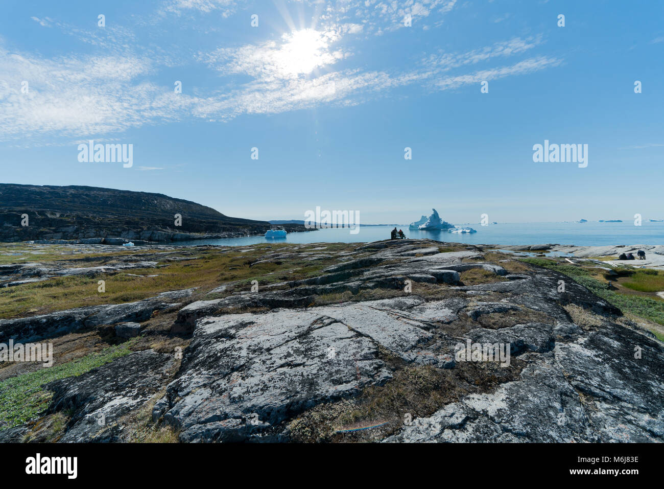2 people on bench in front of icebergs, greenland Stock Photo