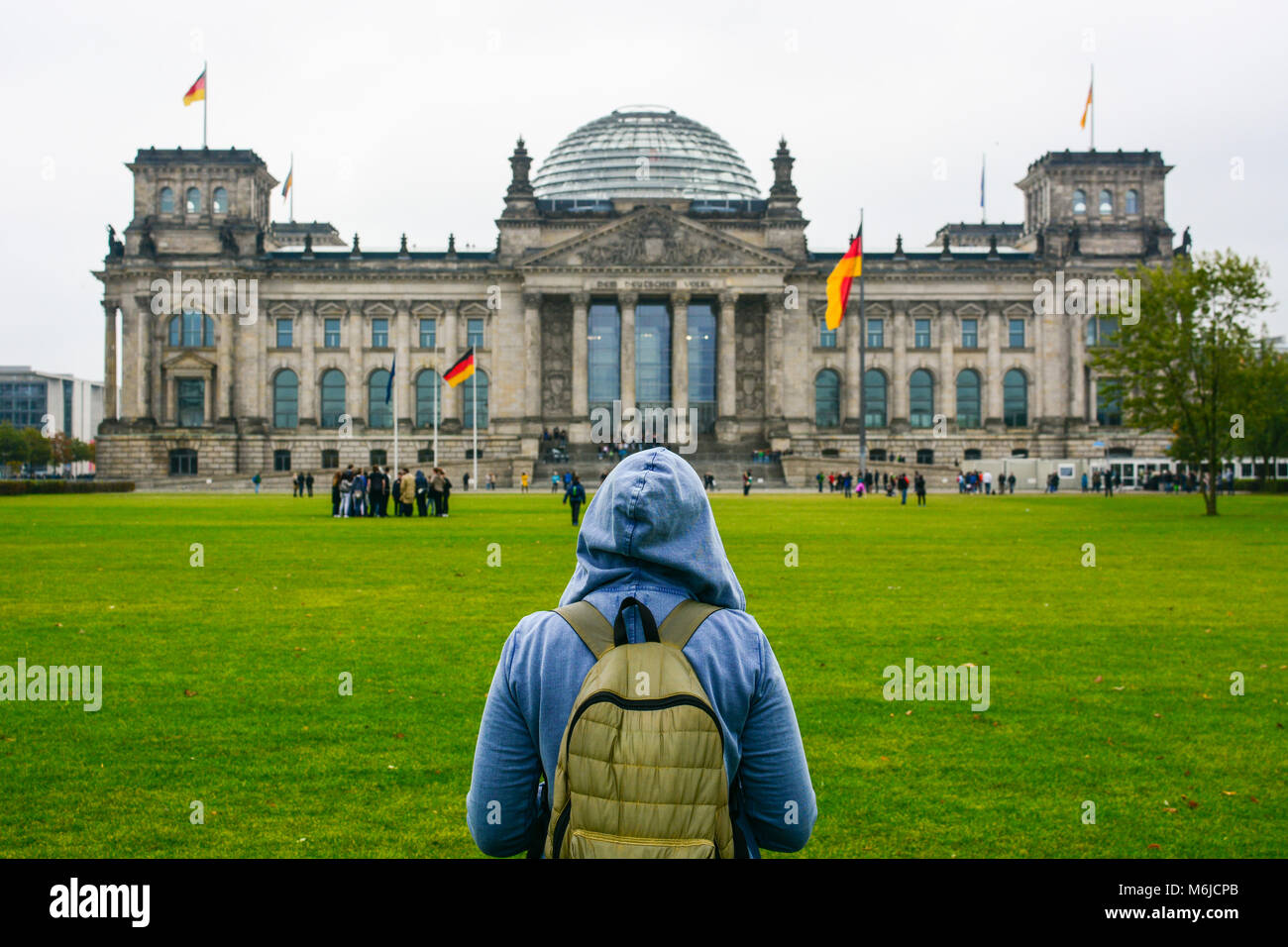 Young woman with backpack looking at Bundestag building in Berlin. Erasmus student, studying abroad and tourist concept. Stock Photo