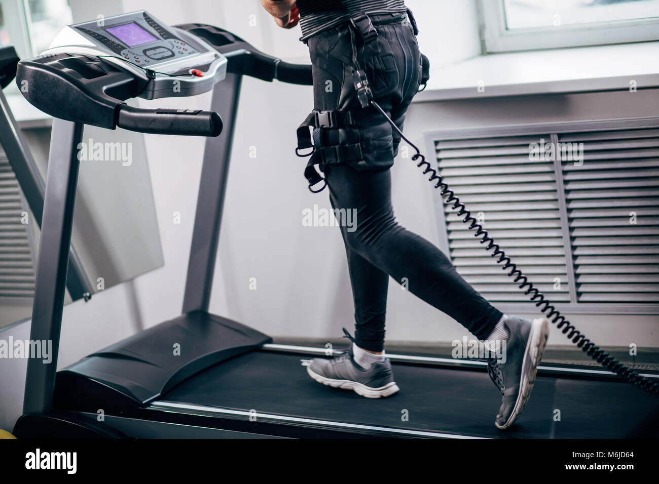 Man in electric muscle stimulation suit for ems training running on