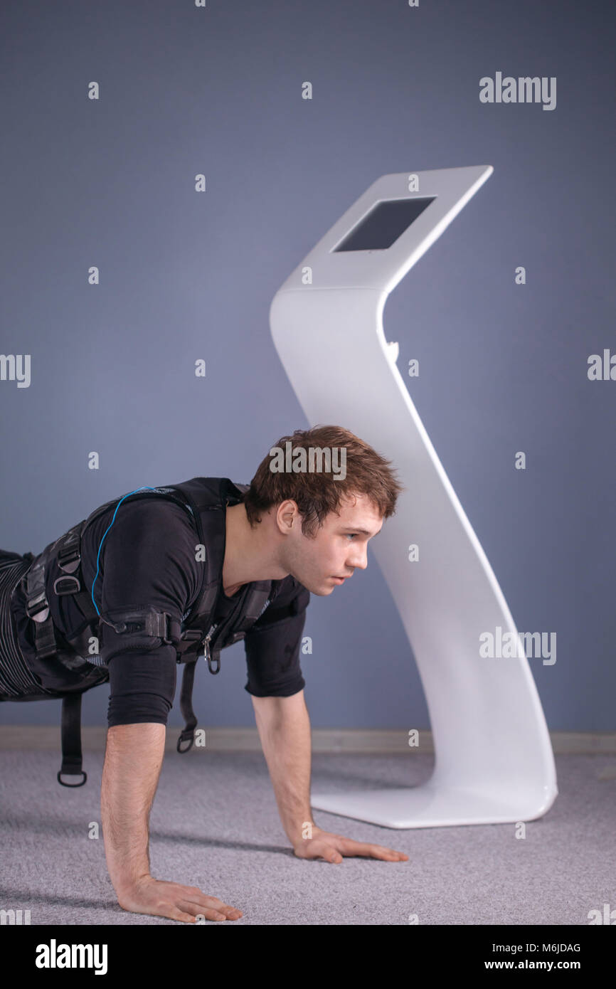 man in Electrical Muscular Stimulation suits doing plank exercise. EMS