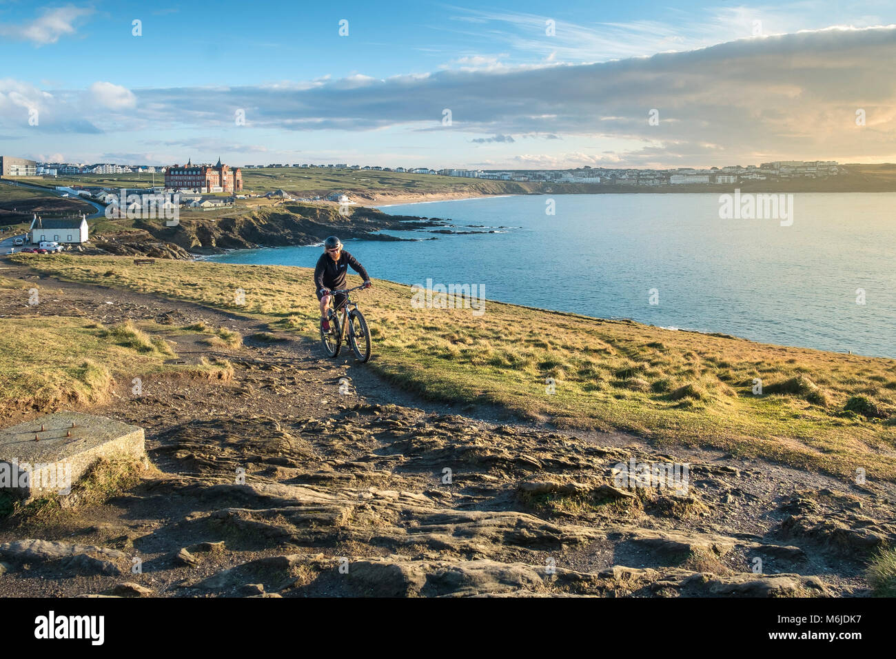 A mountain biker riding up a trail on Towan Head in Newquay Cornwall. Stock Photo