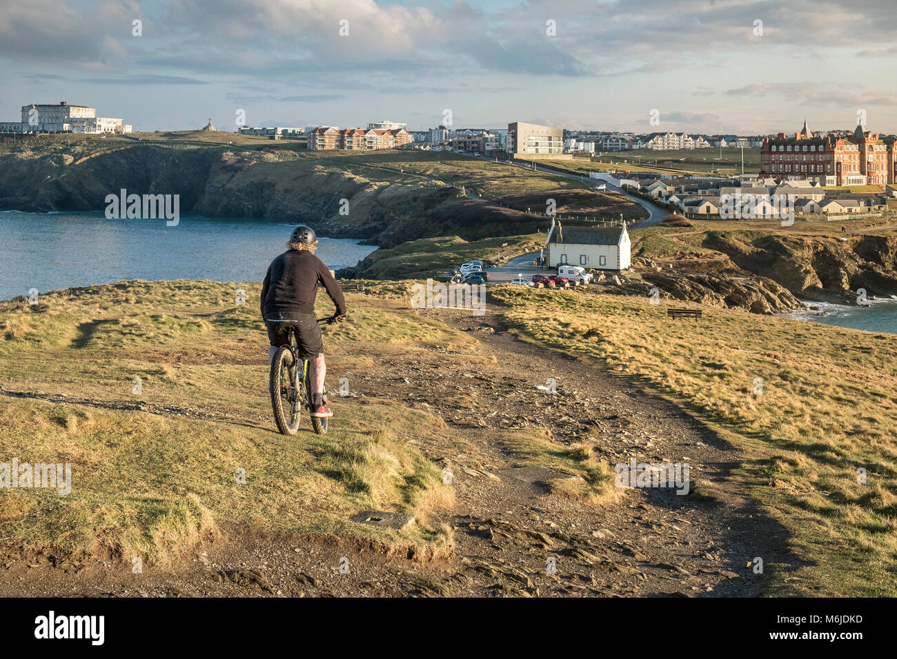 A mountain biker riding down a rough track on Towan Head in Newquay Cornwall. Stock Photo