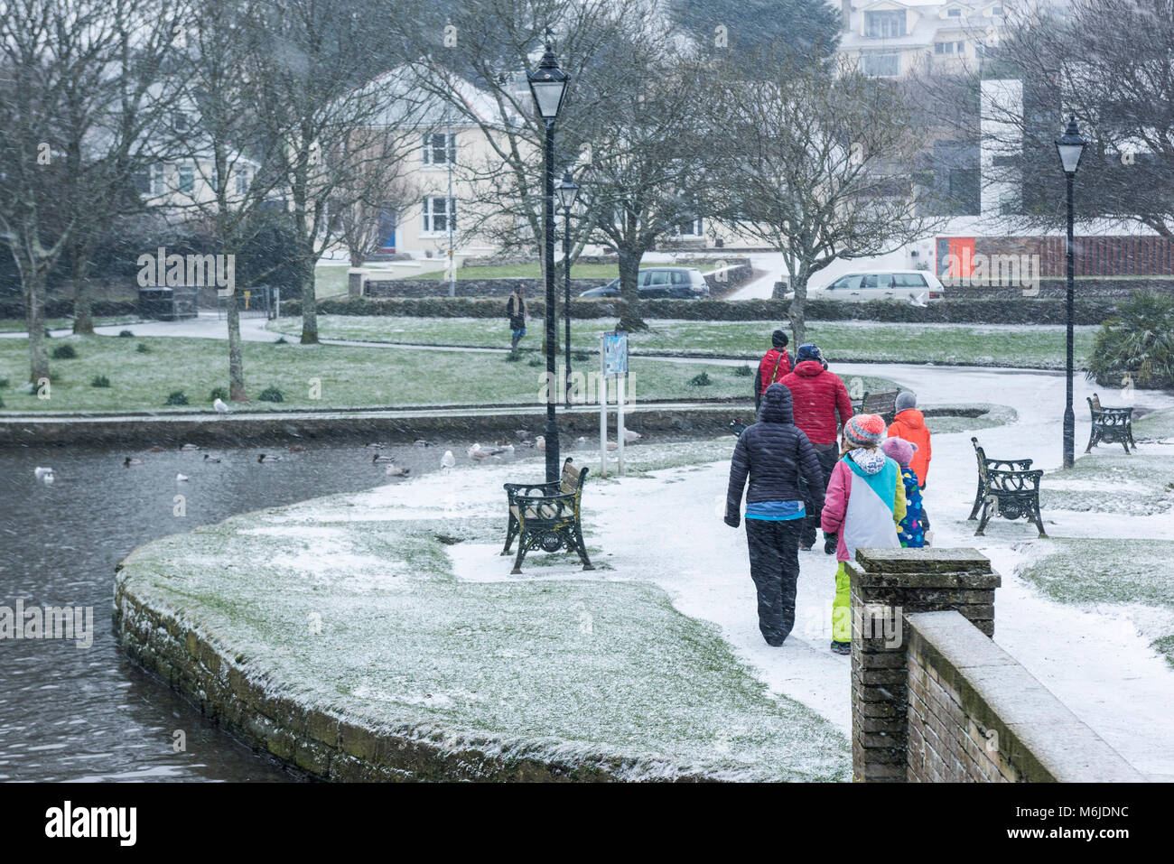 A family wearing brightly coloured clothes during a snow fall in