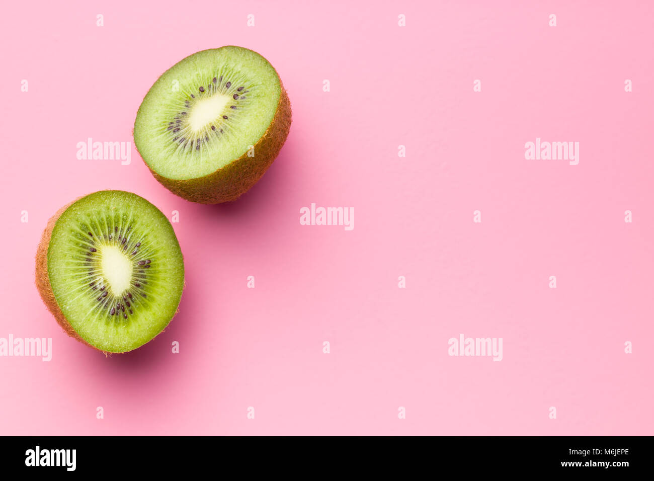 Halved kiwi fruit on pink background. Stock Photo