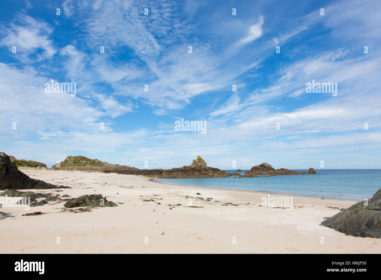 View of a beach at Bailiwick of Guernsey with white sand and rocks. Stock Photo