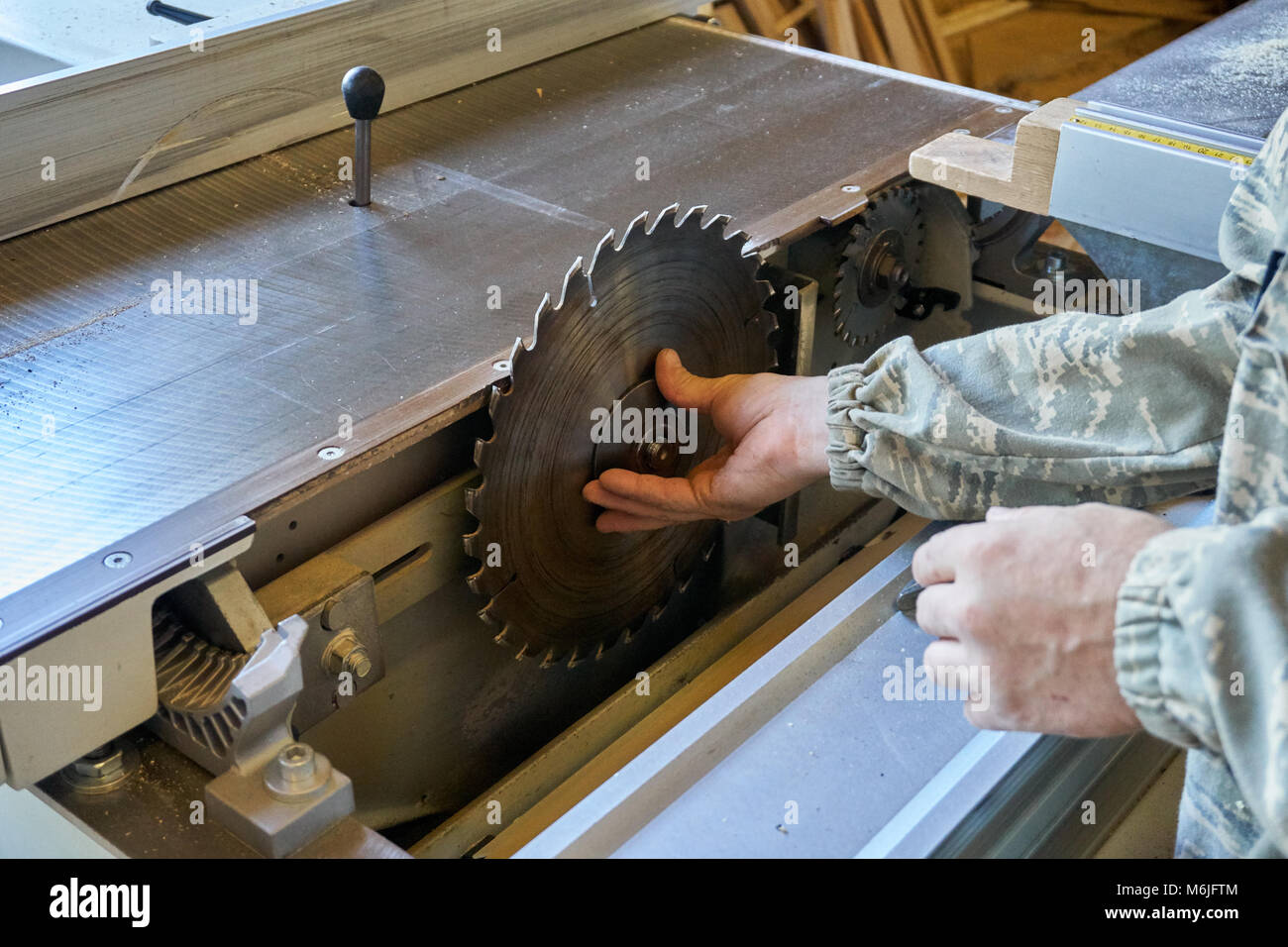 Unrecognizable carpenter sets table saw blade for wood while working in professional