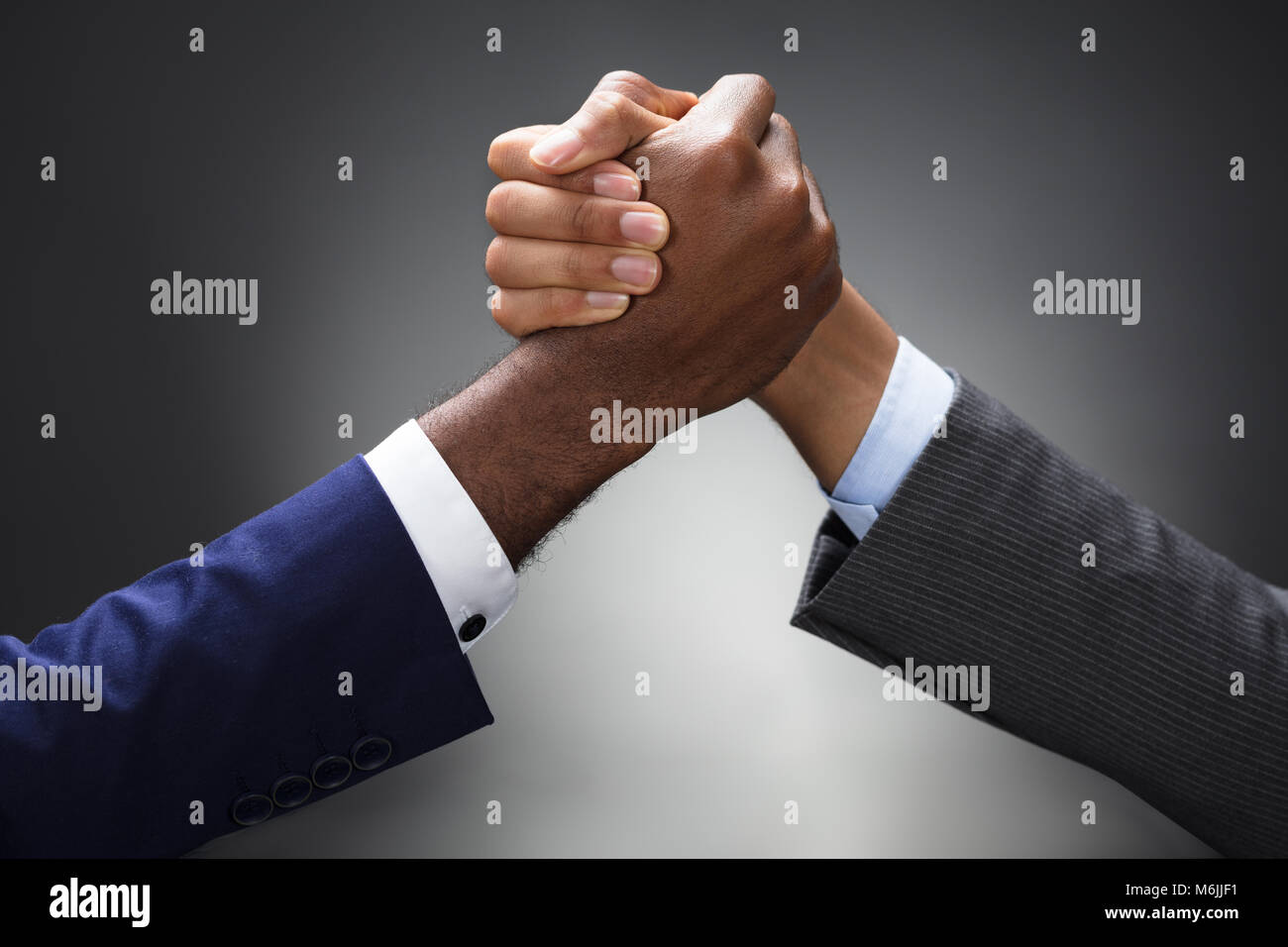 Close-up Of Two Businessman Competing In Arm Wrestling On Gray Background Stock Photo