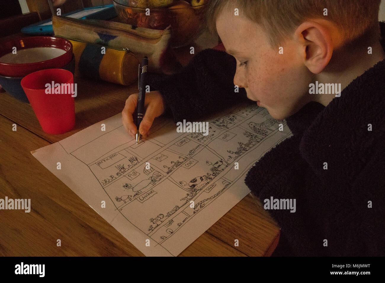 7-year old boy drawing at the breakfast table. Non-digital, non-screen, analogue entertainment. Stock Photo
