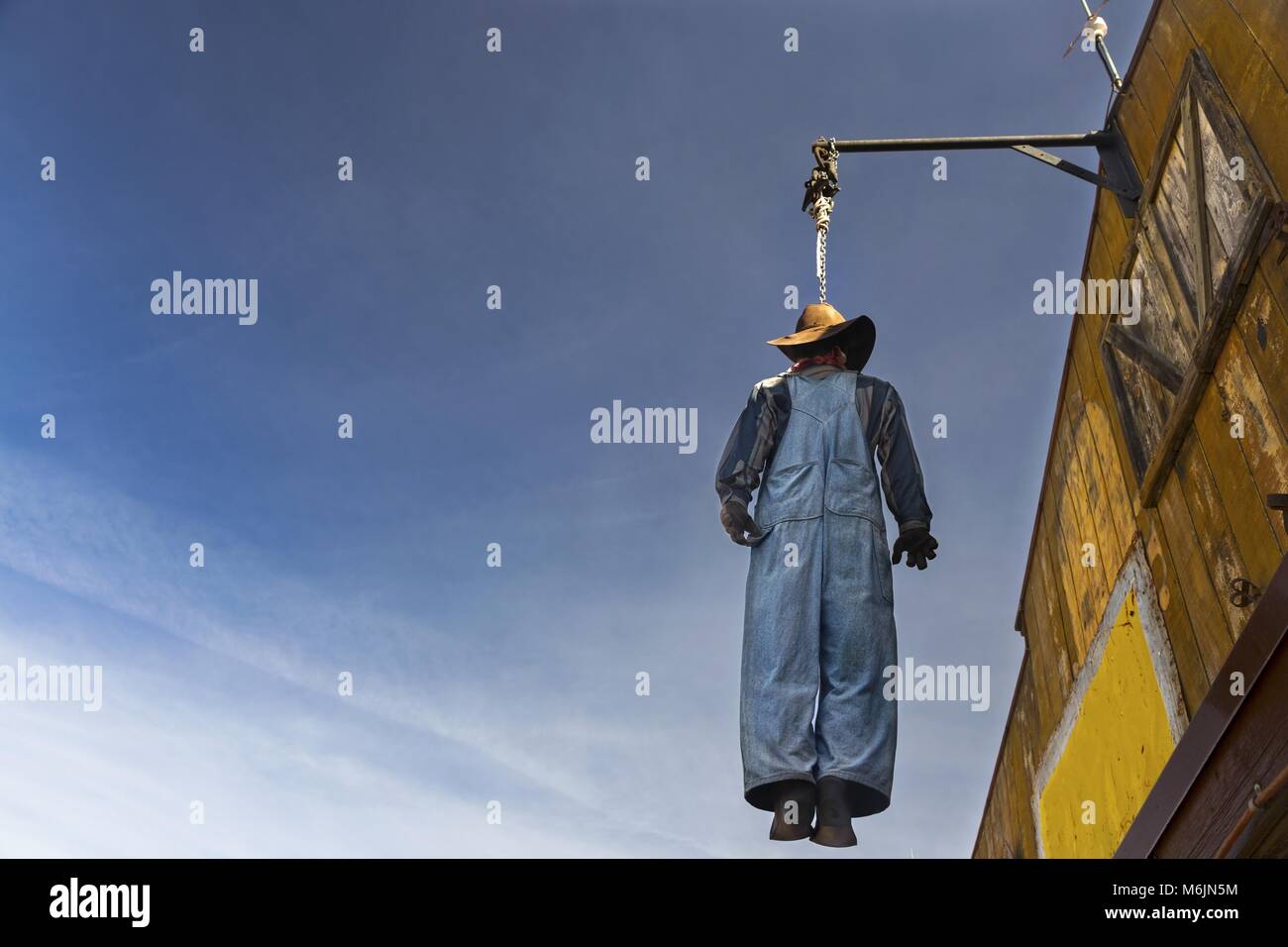 Hay Filled Scarecrow Figure in Country Coveralls and Hat Hanging from Saloon Post in Tortilla Flat Apache Trail east of Mesa Arizona Stock Photo