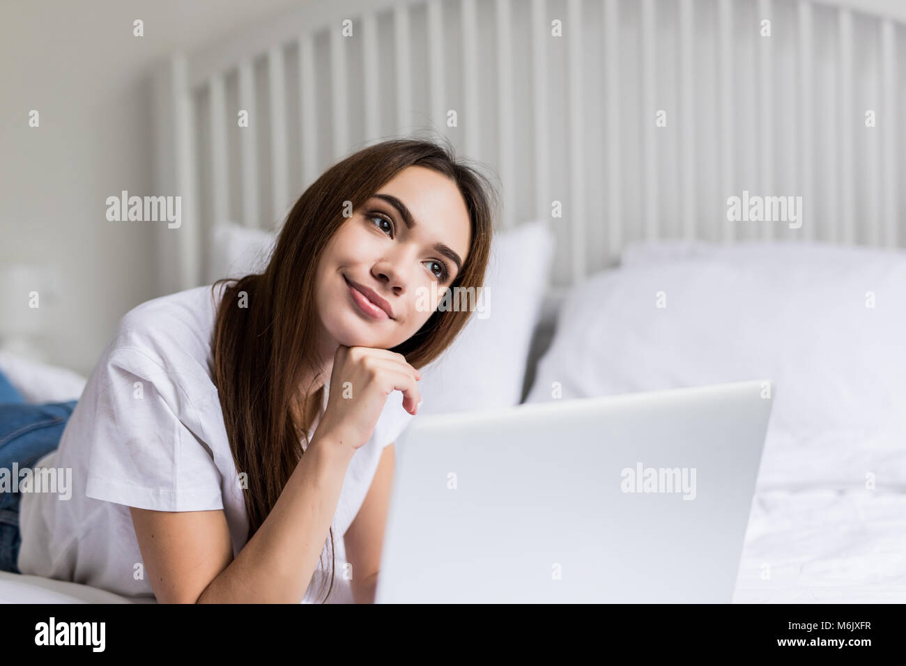 A smiling woman in front of her laptop lying on the bed Stock Photo - Alamy