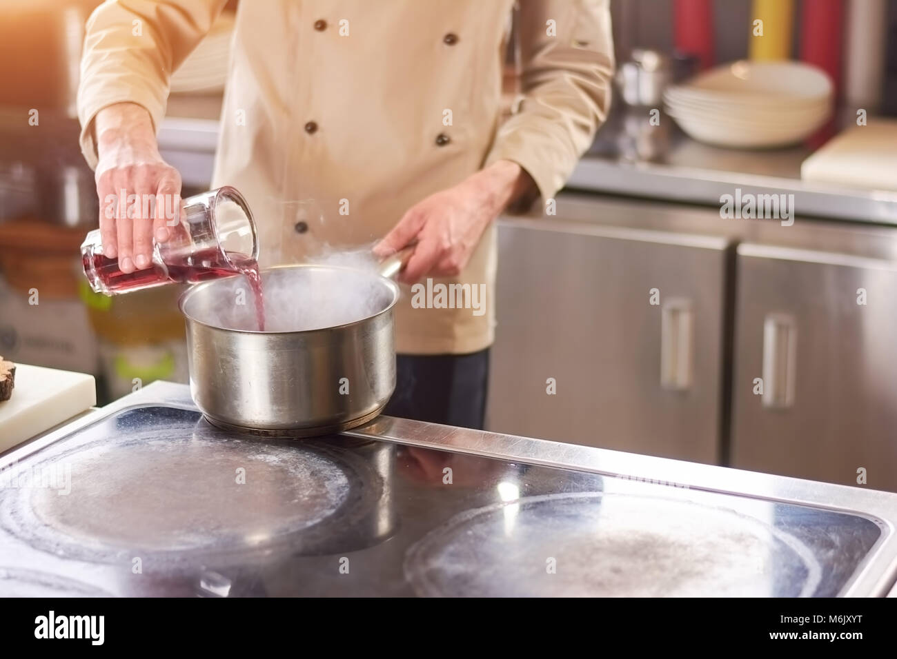 Chef pouring red sauce in casserole. Stock Photo
