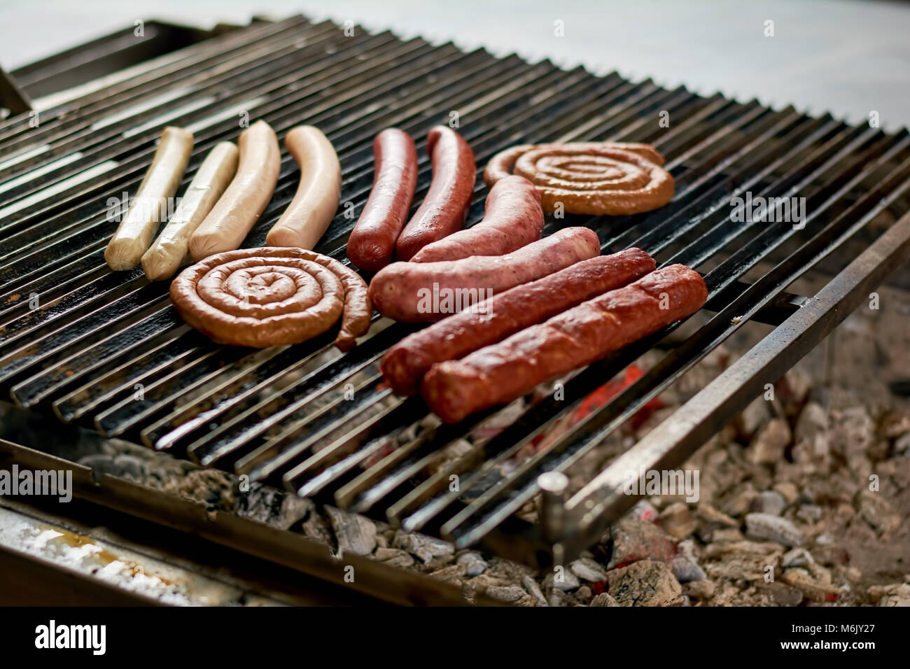 Assorted sausages grilling over coals on barbecue. Stock Photo