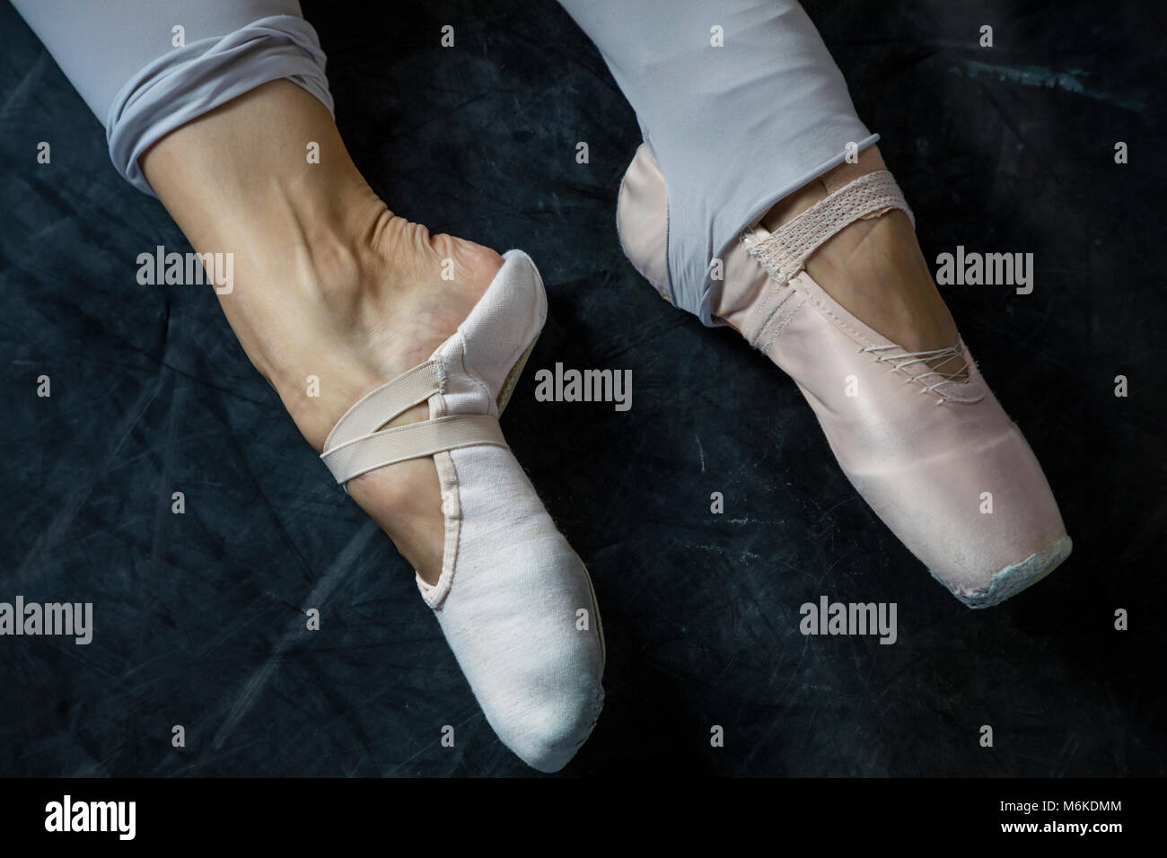 Beautiful legs of young ballerina who changes ballet slippers on pointe Stock Photo