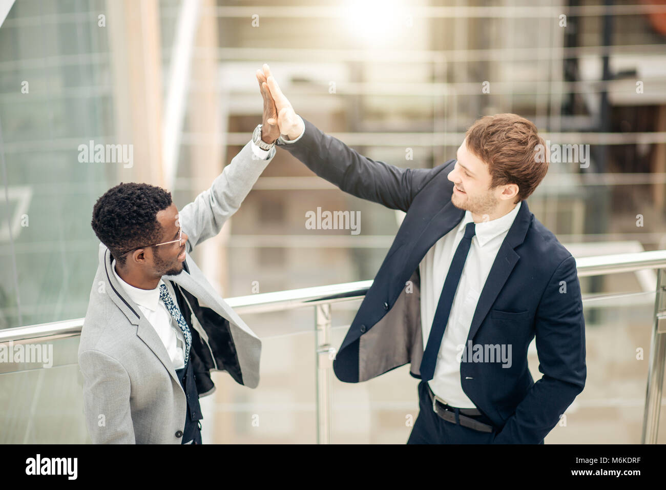 young colleagues giving each other high five while standing in an ...
