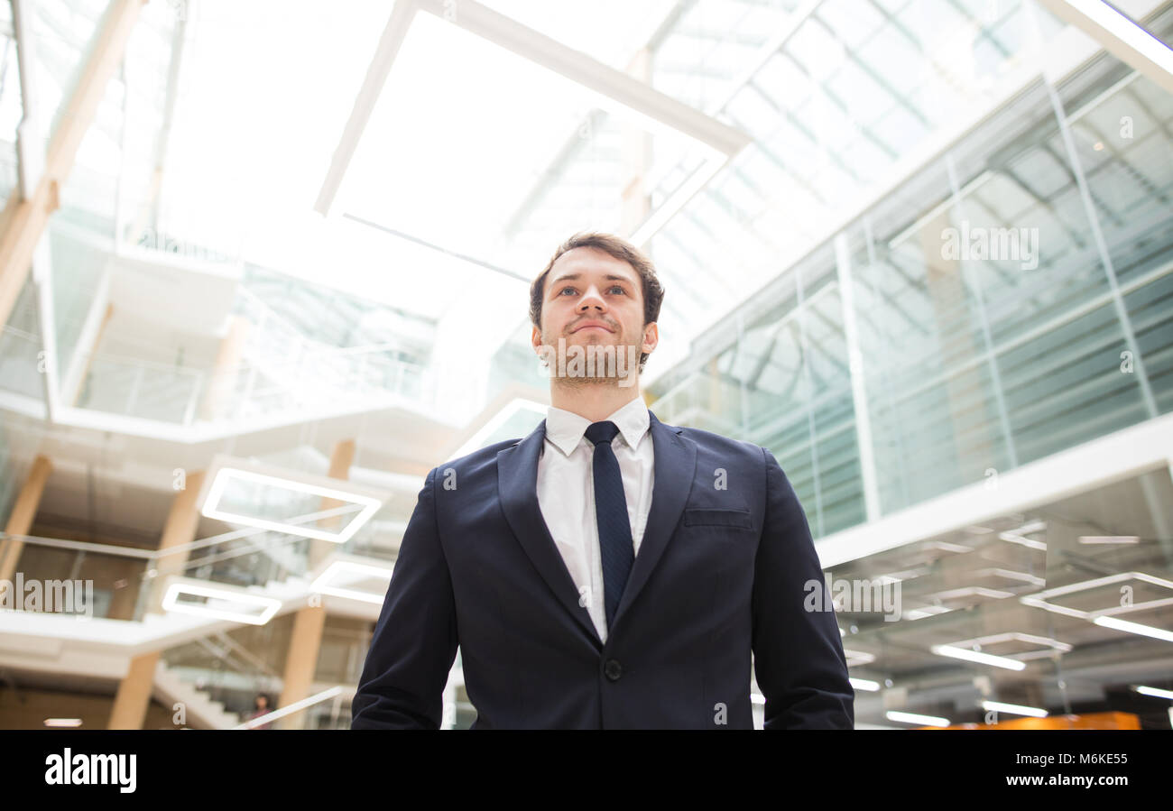confident young businessman standing arms crossed, smiling, looking at ...