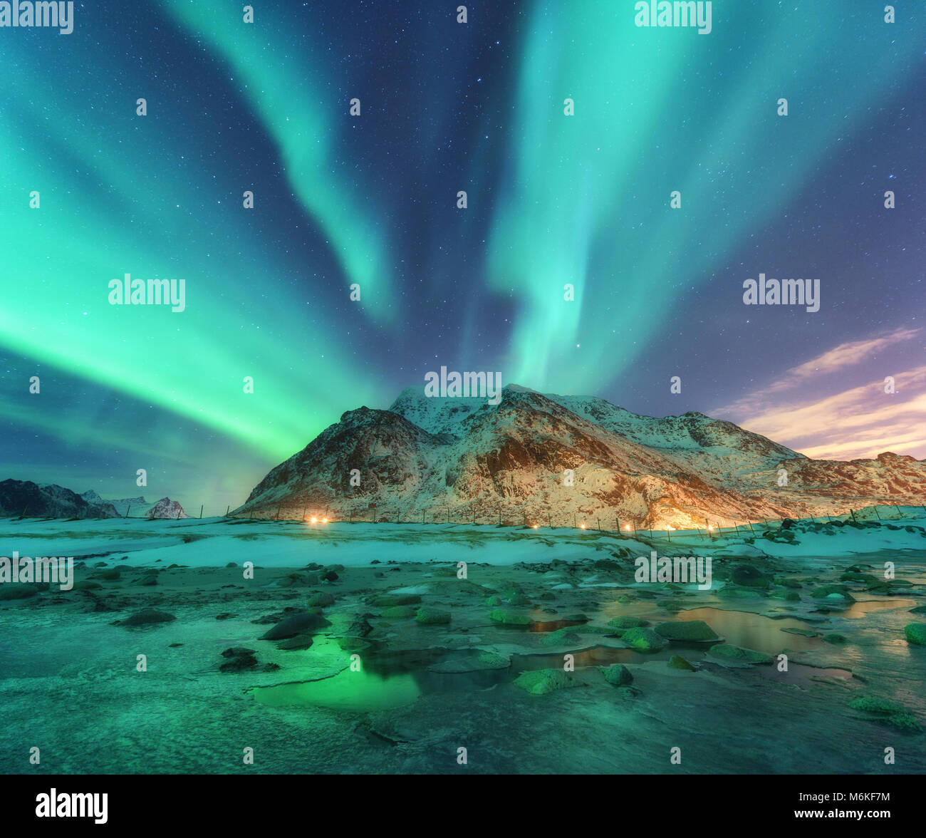 Aurora. Northern lights in Lofoten islands, Norway. Starry sky with polar lights. Night winter landscape with aurora, sea with sky reflection, stones, Stock Photo