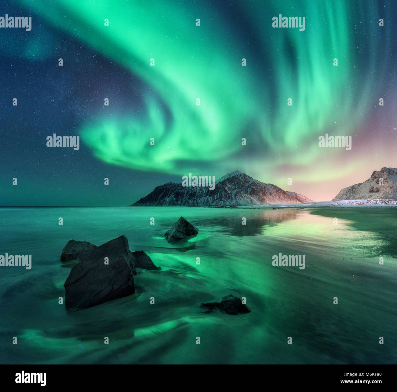 Aurora borealis on the Norway. Green northern lights above mountains. Night  sky with polar lights. Night winter landscape with aurora and reflection on  the water surface. Natural back Stock Photo