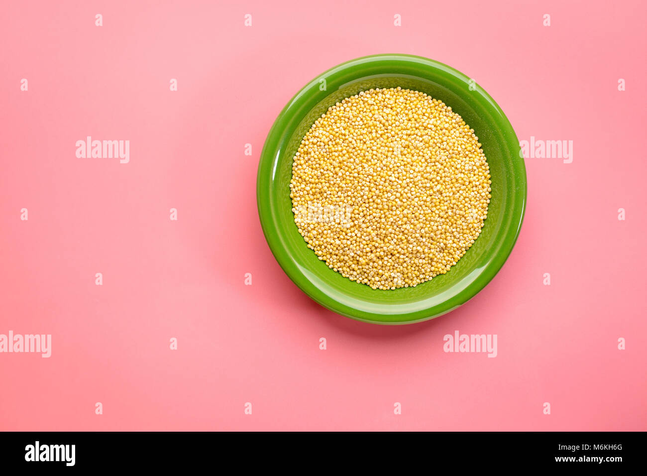gluten free hulled millet grain in a ceramic bowl against pink