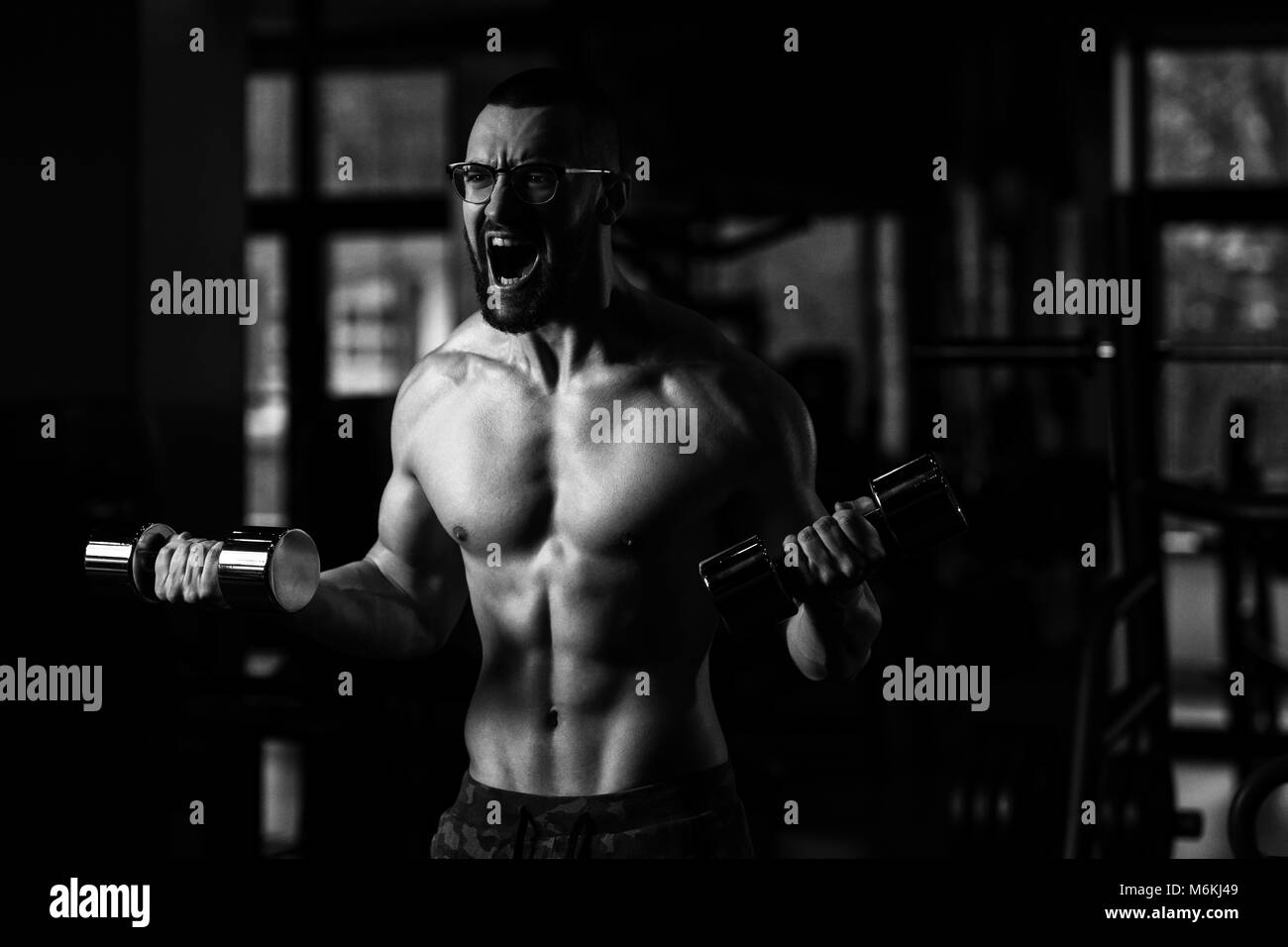Handsome Man Wearing Glasses Working Out Biceps In A Dark Gym - Dumbbell  Concentration Curls Stock Photo - Alamy