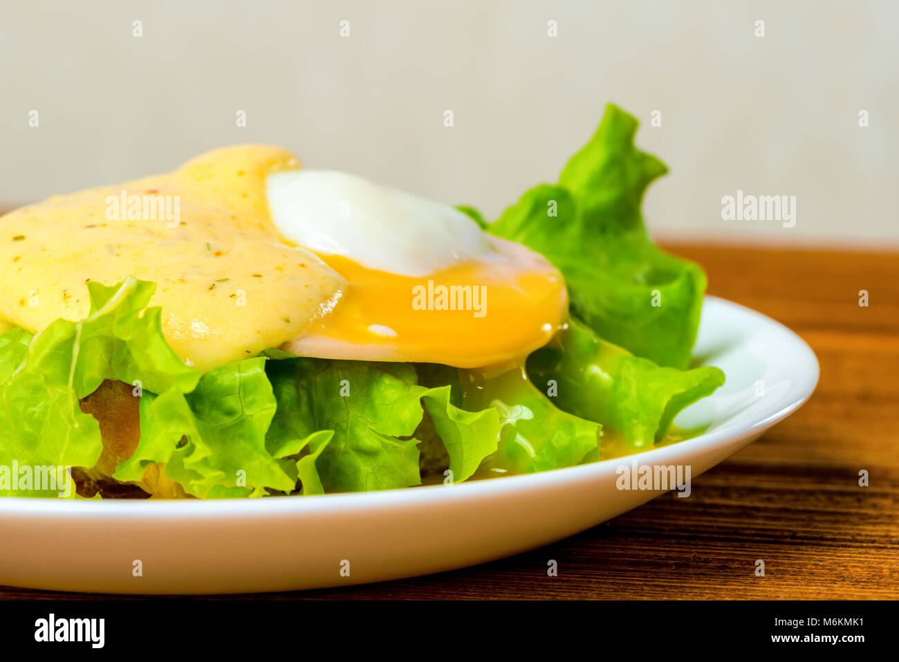 closeup poached eggs, ham, lettuce leaf and delicious buttery fresh