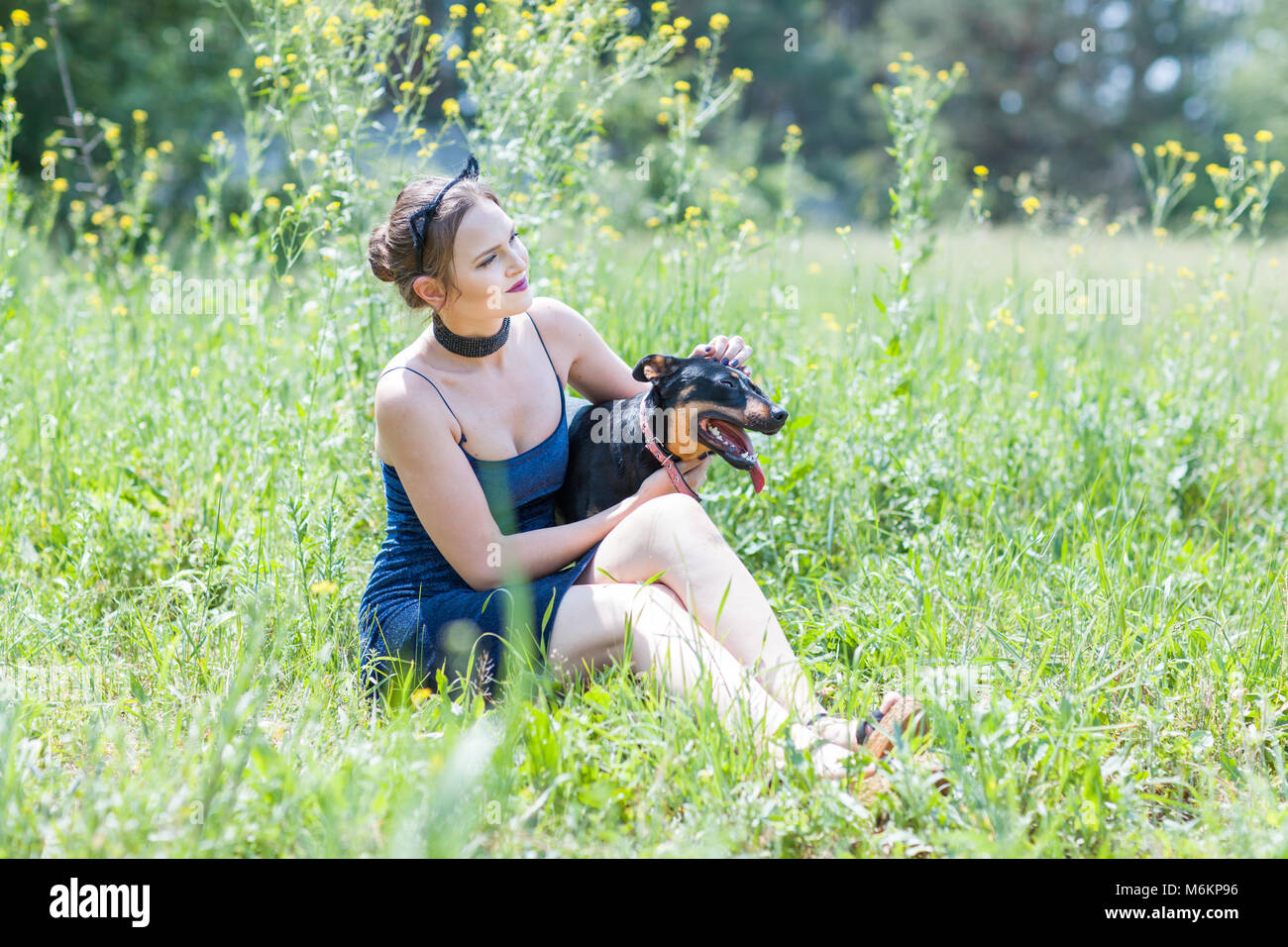 Adorable girl and dog are sitting on the grass in the field Stock Photo ...