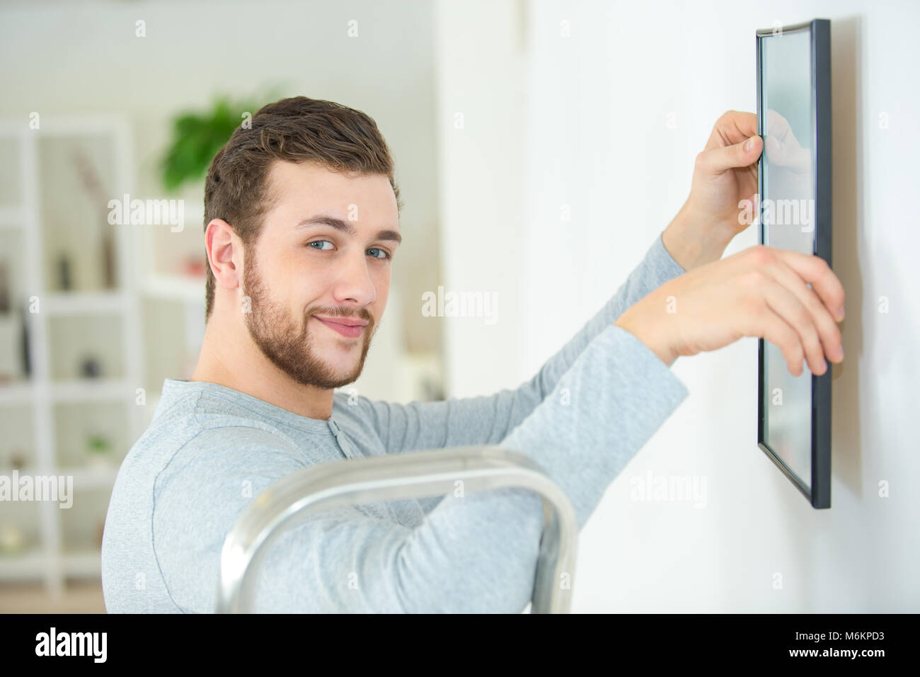 man positioning picture frame on wall Stock Photo Alamy