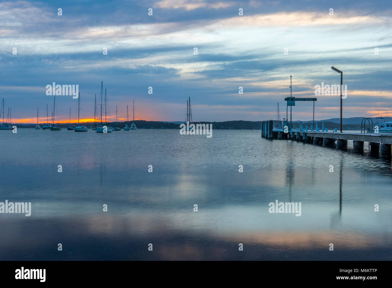 Sunset at Lake Macquarie with Belmont Wharf in foreground and sailing boats in background. Belmont. AUSTRALIA Stock Photo