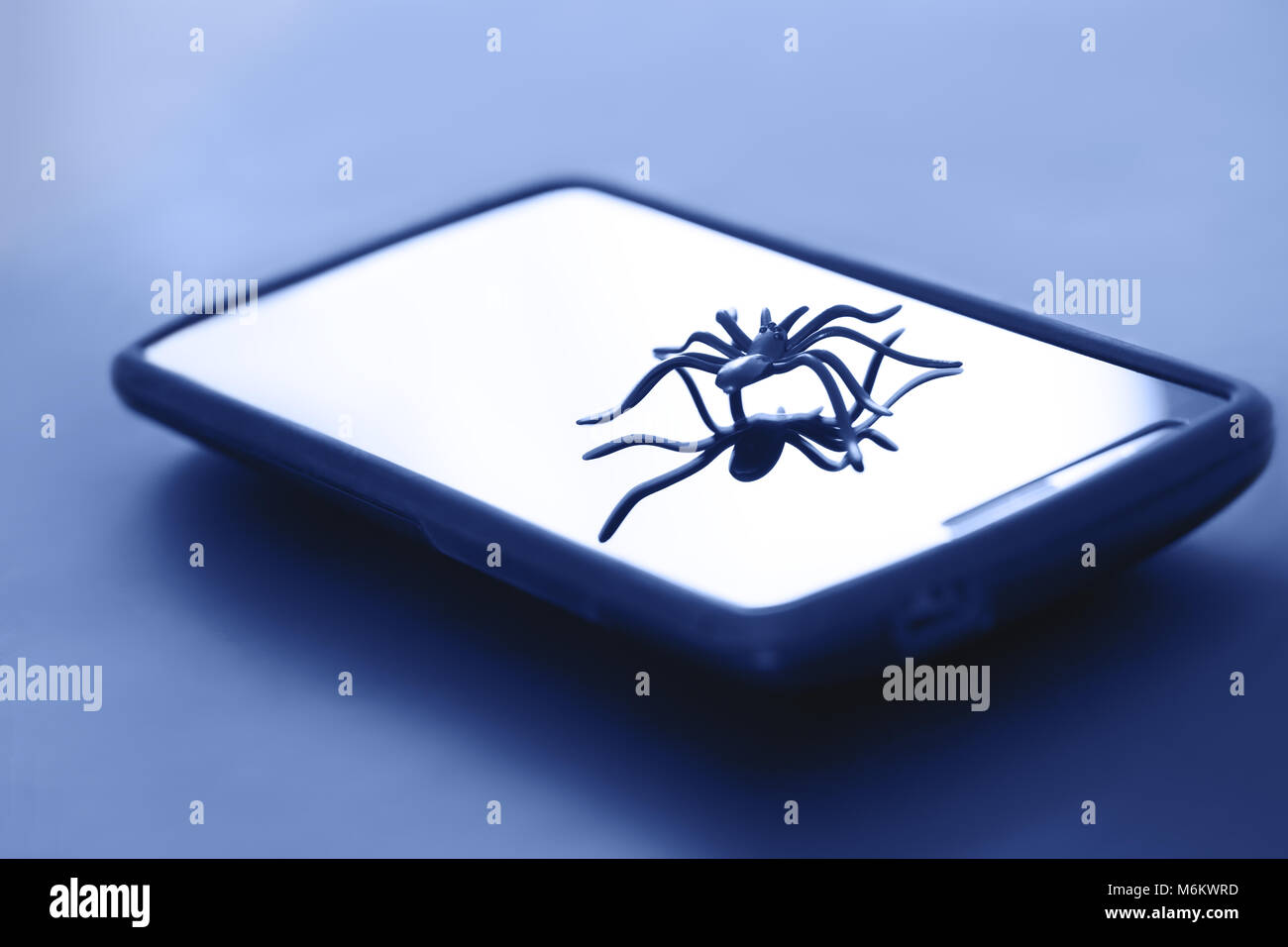 Cute spider toy posing on surface of gadget display. Plastic spider toy in action on surface of device screen. Best picture for digital communication. Stock Photo