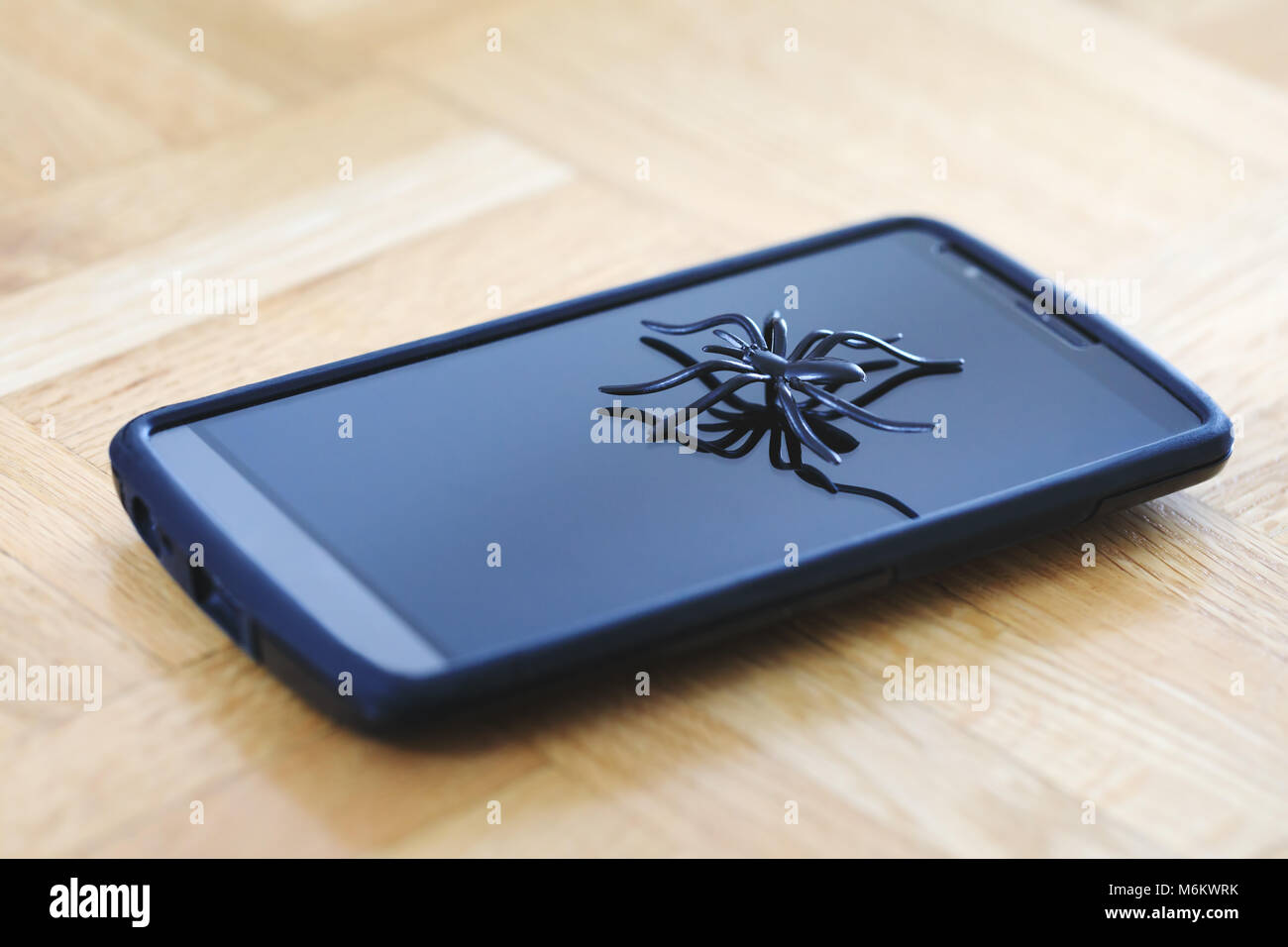 Great spider toy posing on surface of cellphone. Plastic spider model toy in action of running on surface of device display. Telecommunications. Stock Photo
