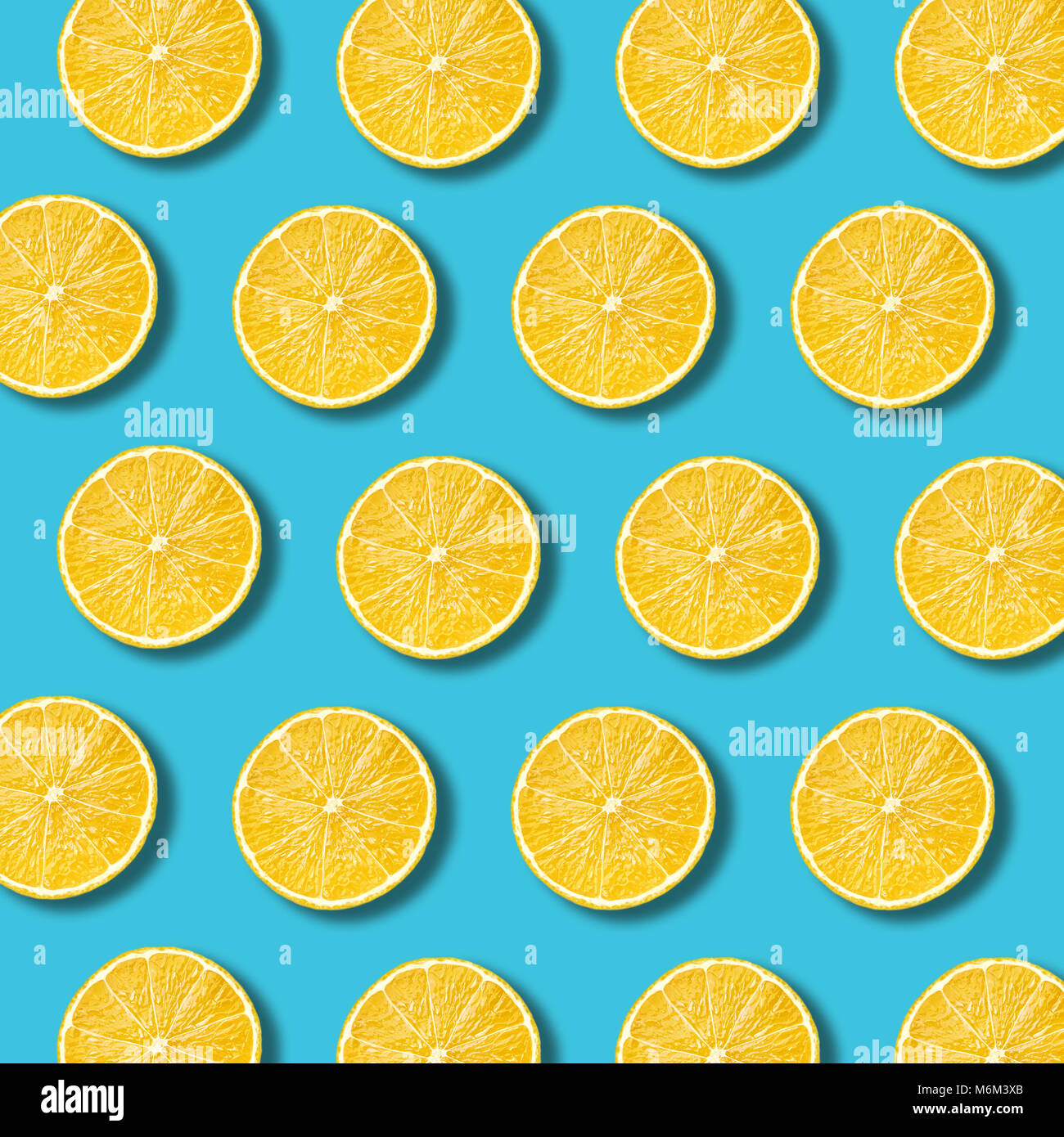 Lemon slices pattern on vibrant turquoise color background. Minimal flat lay food texture Stock Photo