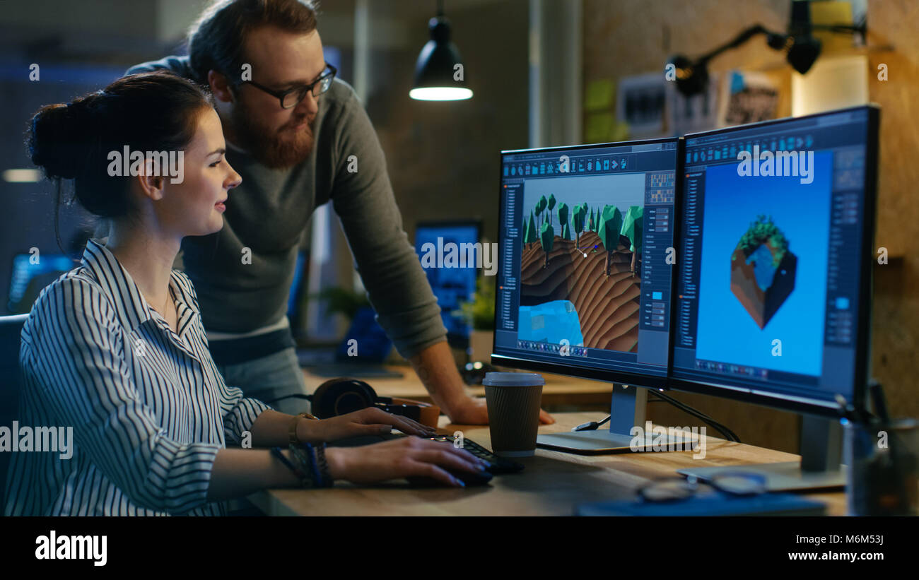 Female Game Developer Has Discussion with Male Project Manager While Working on a Game Level on Her Personal Computer with Two Displays. Stock Photo