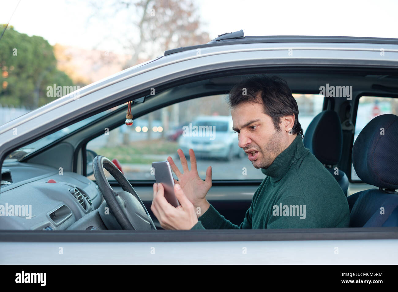 Rude man driving his car and distracted by mobile phone Stock Photo