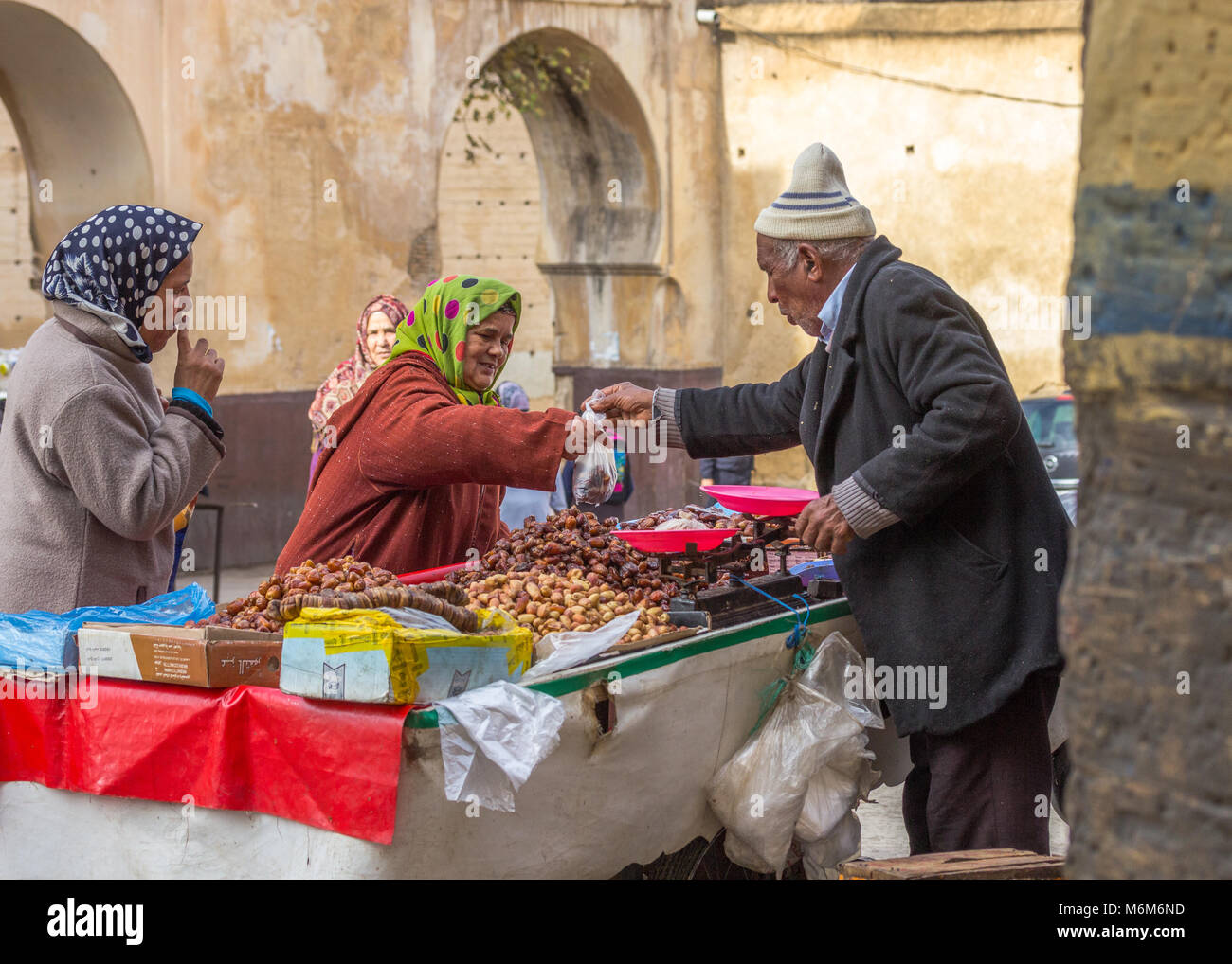 An elderly woman buys dates from a street seller, selling from a cart in the muslim quarter of Fes el-Jedid, Res, Morocco Stock Photo