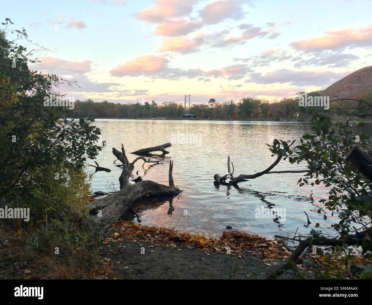 Sunset over a mountain lake with a suspension bridge peaking over the ...