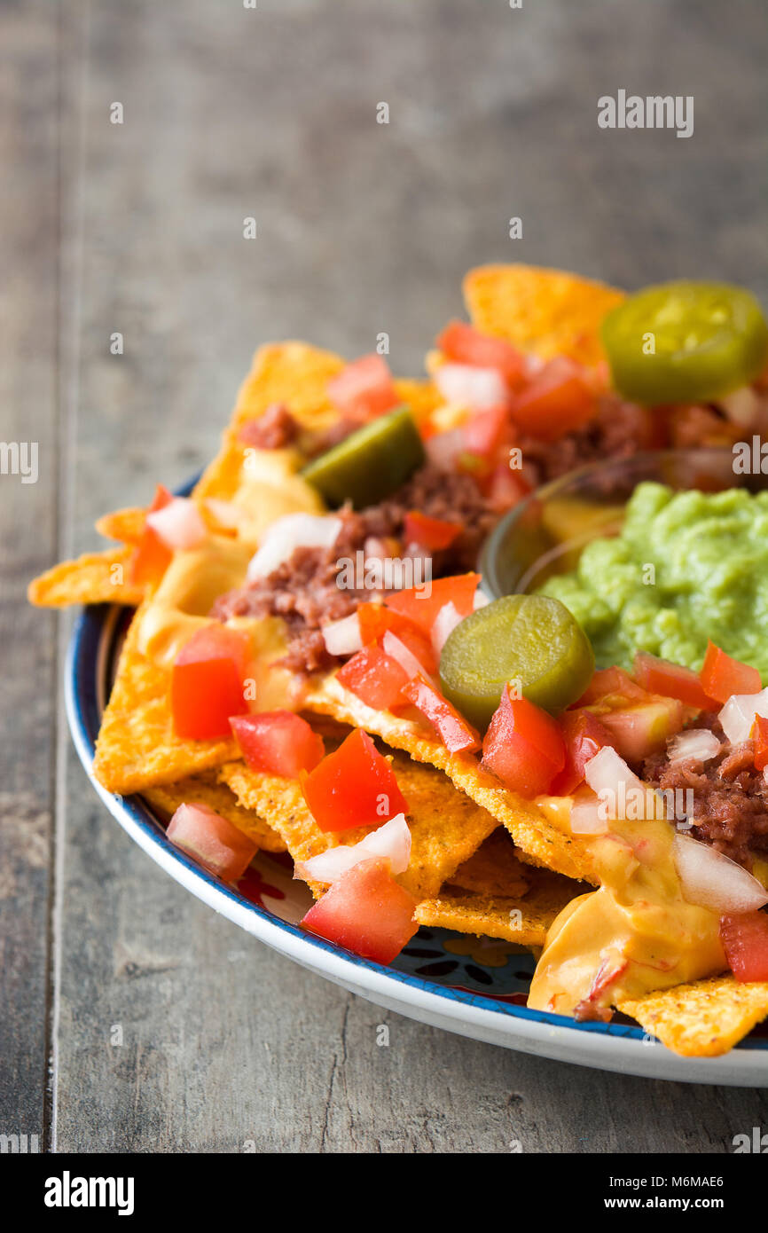 Mexican nachos with beef, guacamole, cheese sauce, peppers, tomato and ...