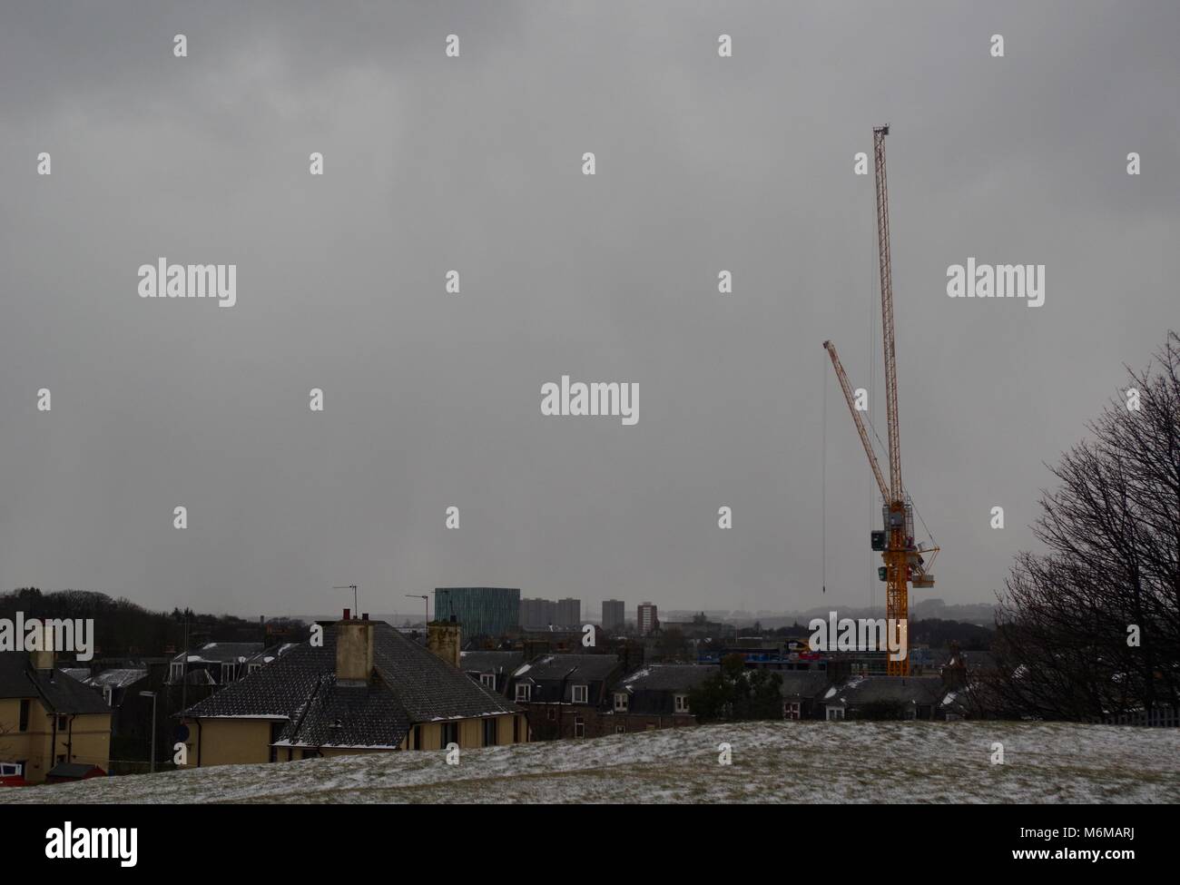 Yellow Crane on a Construction Site, Looking Towards Aberdeen University Campus on a Grey Cold Day. Beast from the East Snow Storm. Scotland UK. Stock Photo