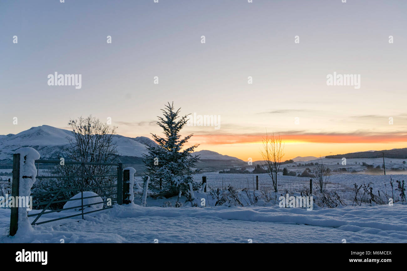 Beautiful sunset on a scottish valley covered in snow in the Highlands with mountains in the background and a clear sky ideal for copyspace Stock Photo