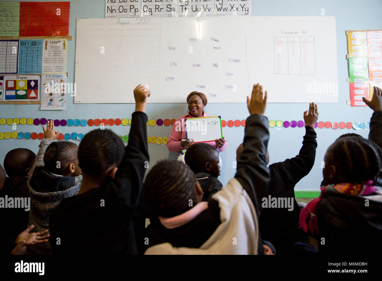 Children raising their hands to answer the teacher Stock Photo