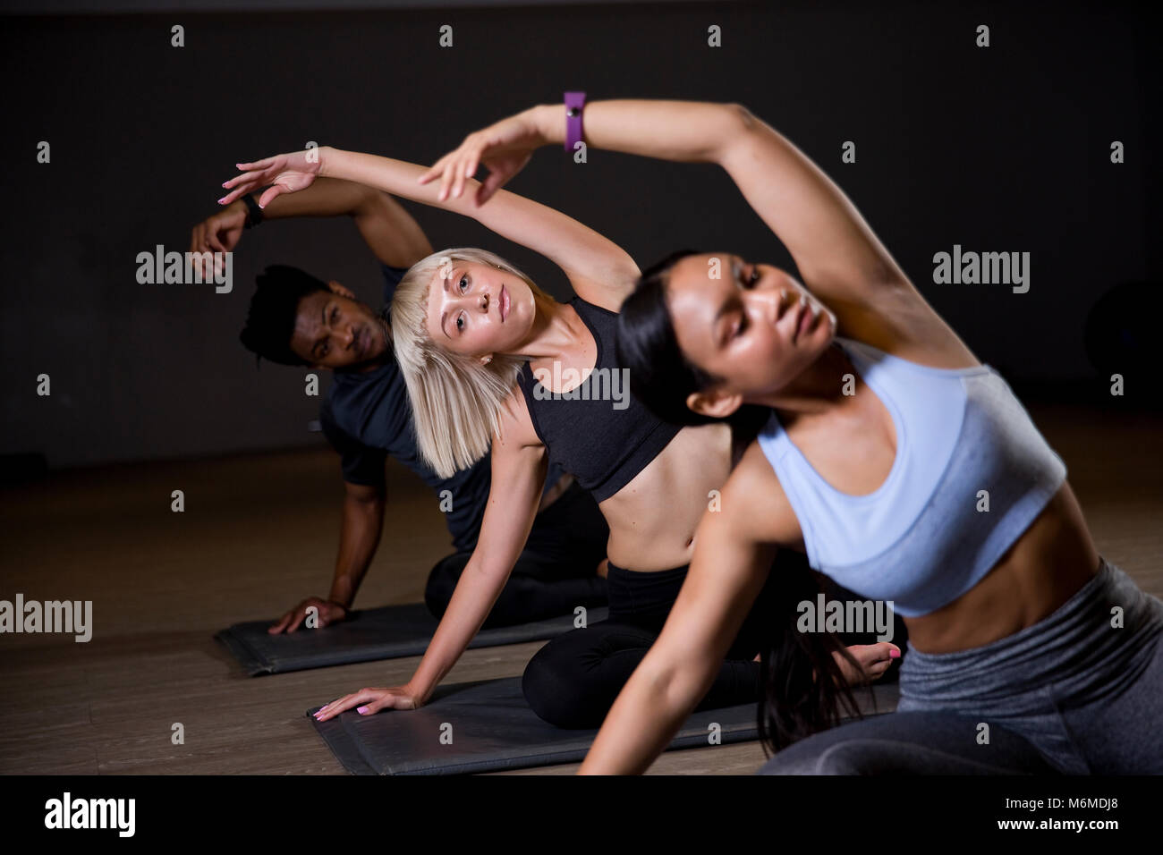 People with arms raised in yoga class Stock Photo