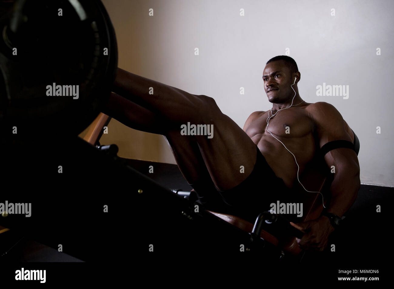 African man listening to cell phone and exercising in gym Stock Photo