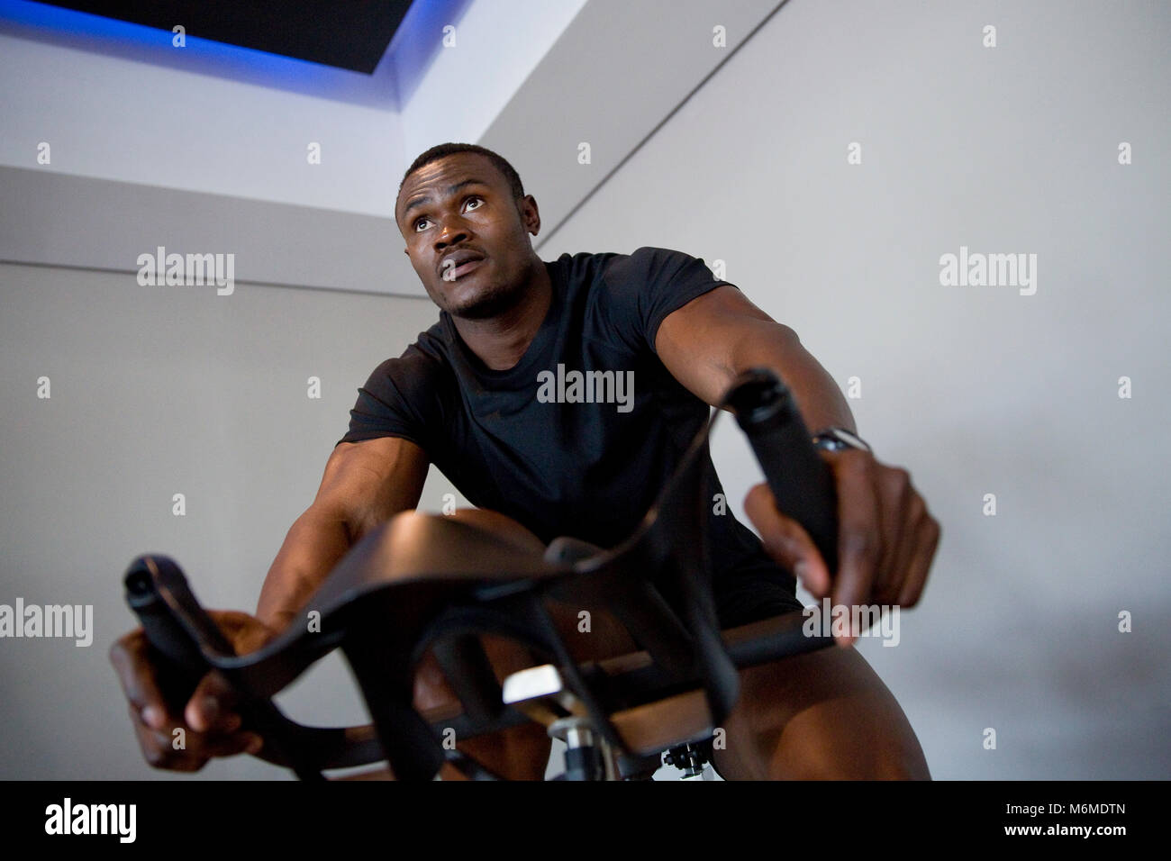African man exercising on stationary bicycle Stock Photo