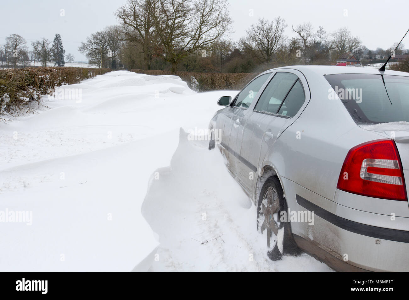 A car stuck in a snow drift in a country lane in Redditch, UK Stock Photo